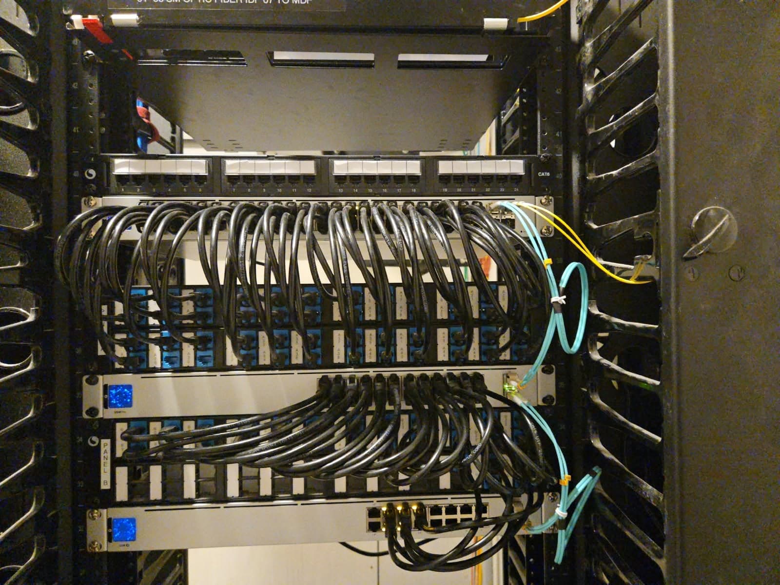 Rack de cableado estructurado con paneles Cat6 etiquetados y latiguillos de fibra aqua y amarilla