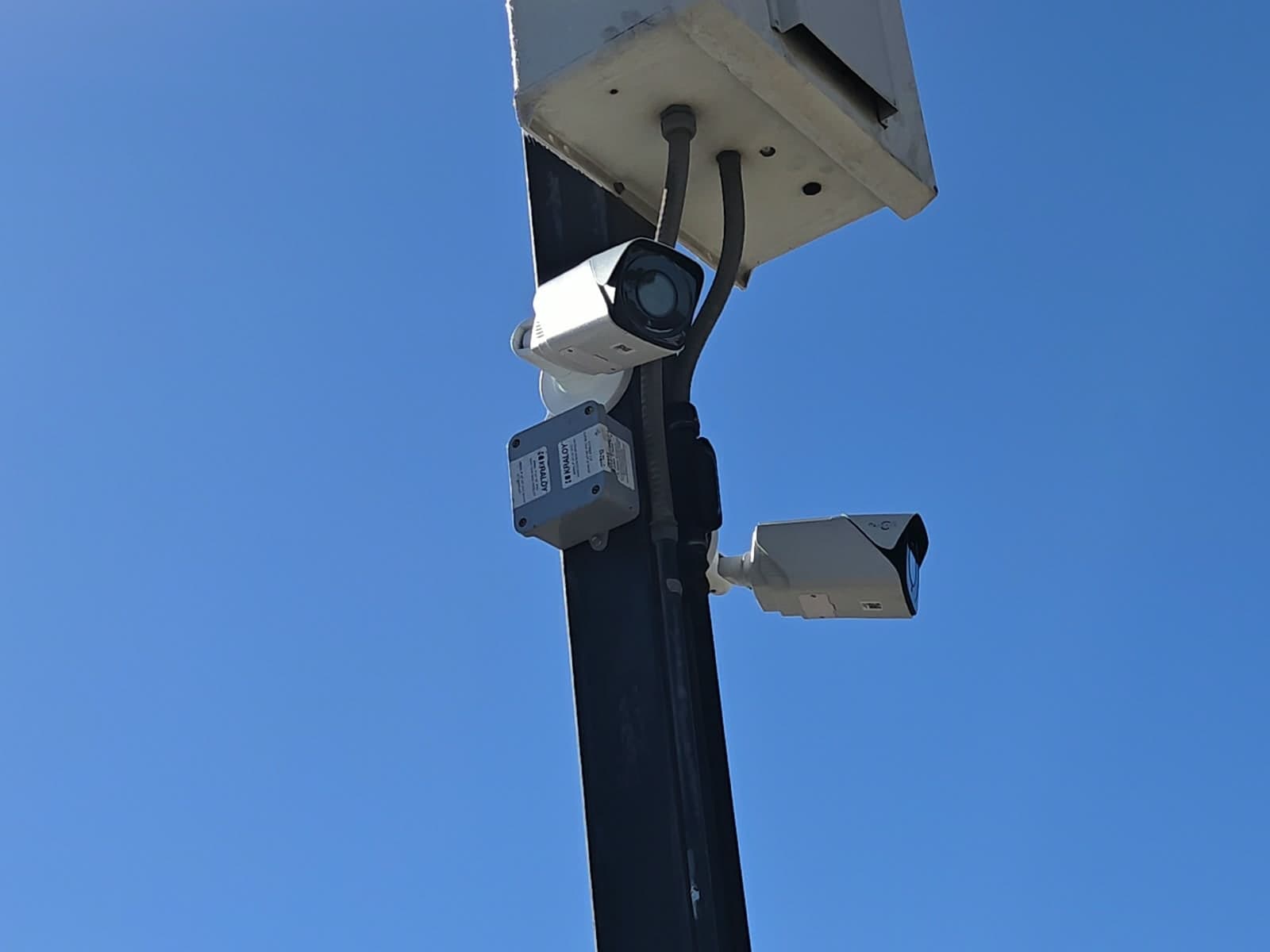 Dos cámaras de seguridad tipo bala montadas en un poste contra un cielo despejado